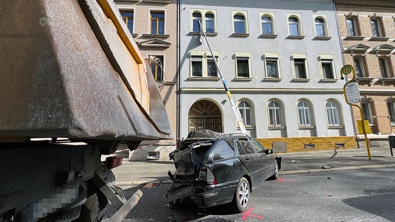 Laternenmast nach Unfall zwischen Pkw und Lkw gegen Hauswand gekippt.