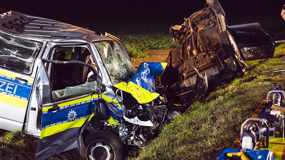 Ein beschädigter Polizeiwagen und ein Auto liegen im Straßengraben.