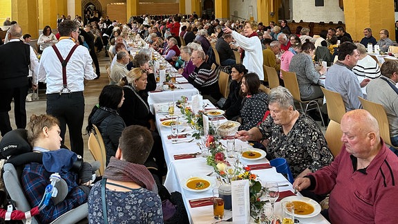 Menschen an einem langen Tisch in einer Kirche. 