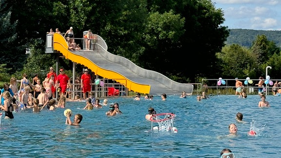 Menschen schwimmen im Jenaer Ostbad in einem Außenbecken.