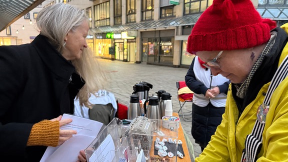 "Omas gegen Rechts" bei einer Kundgebung in Jena. Andrea und zwei ihrer Mit-Omas bauen den Infotisch auf.