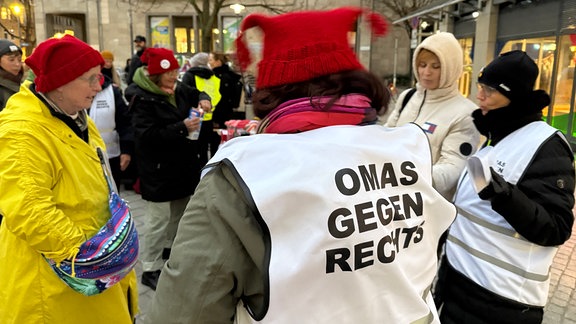 "Omas gegen Rechts" bei einer Kundgebung in Jena, Omas am Infotisch, eine mit einer Weste mit der Aufschrift "Omas gegen Rechts"