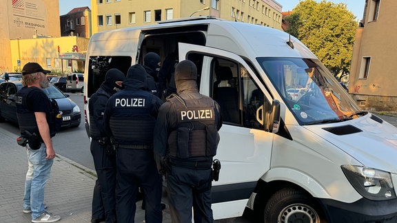 Polizisten stehen vor einem Streifenwagen. 