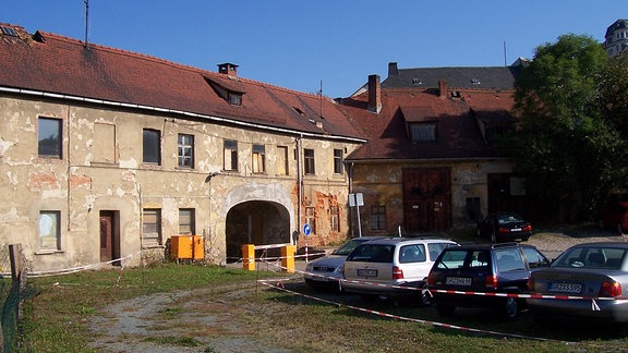 Autos stehen in einem abgesperrten Bereich vor einem Haus.