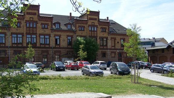 Autos stehen auf einem Parkplatz vor einem Haus.