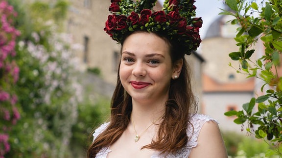 Eine Frau im Kleid mit einer Rosenkrone auf dem Kopf.