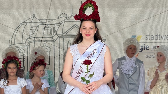 Eine Frau im Kleid mit einer Rosenkrone auf dem Kopf.