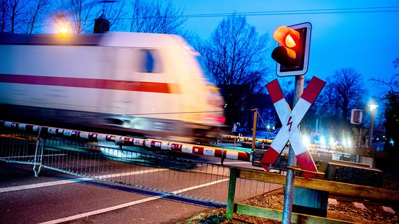 Ein Andreaskreuz und eine rot leuchtende Ampel stehen an einem geschlossenen Bahnübergang