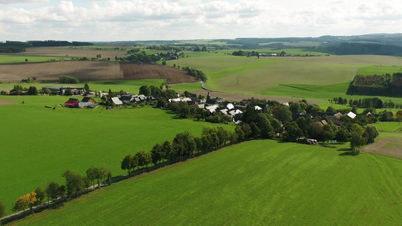 Blick auf eine dörfliche Siedlung an einem Berg.