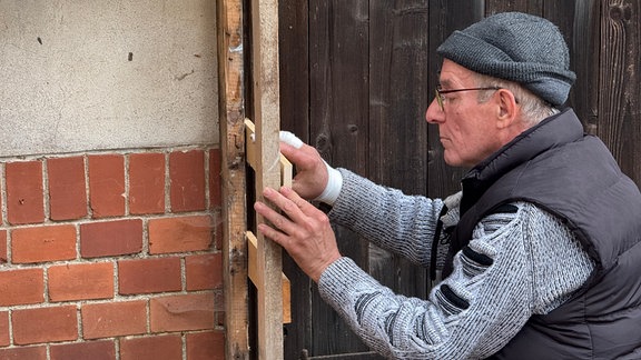 Mann arbeitet mit Holz an einem Haus