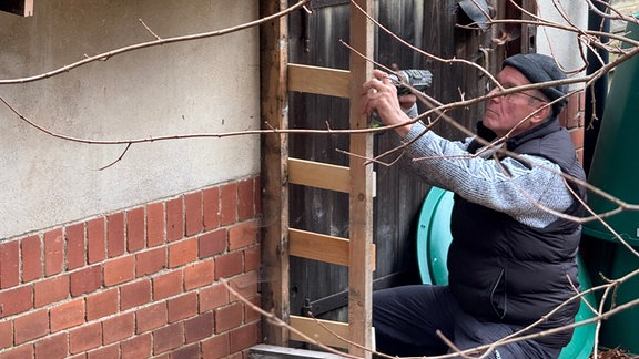 Mann arbeitet mit Holz an einem Haus