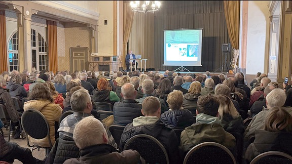 Günter Wetzel berichtet im Pößnecker "Rosengarten" von der Vorbereitung und Durchführung der Flucht mit dem Ballon, die Plätze im Saal sind gut besetzt.