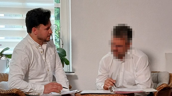 Aimal Nabizada und sein Bruder sitzen an einem Tisch und bearbeiten Anträge.