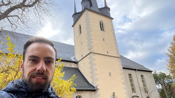 Ein Mann steht vor einer Kirche