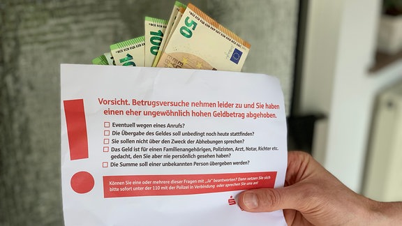 Umschlag mit Bargeld und Hinweisen der Sparkasse, gegen Betrug