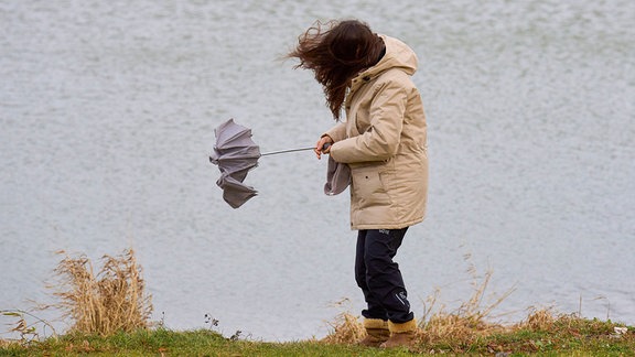 Eine Frau mit Regenschirm bei stürmischem Wetter