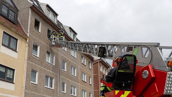 Feuerwehrauto steht mit ausgefahrener Drehleiter vor Mehrfamilienhaus