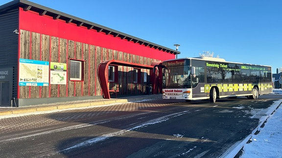 Ein Bus fährt auf einen großen Parkplatz. 