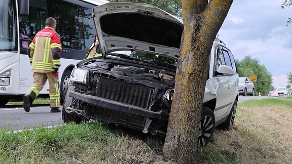 Ein Feuerwehrmann läuft hinter einem beschädigten Auto entlang. 