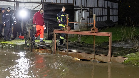 Feuerwehrleute und Rettungssanitäter stehen an einem Wehr