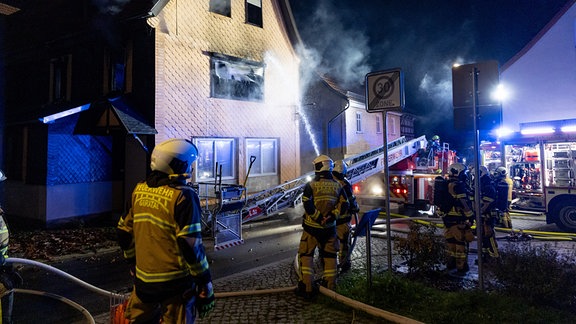 Die Feuerwehr steht vor einem Haus.