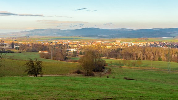 Ein Panoramablick auf Breitungen im Werratal. Grüne Felder im Vordergrund. Leicht bewölkter Himmel.