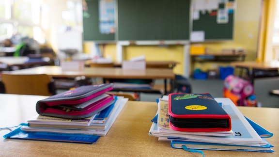 Federmappen und Hefte liegen auf einem Tisch in einer Grundschule.