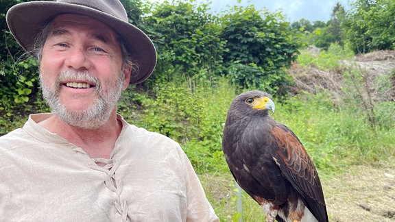 Ein Falkner mit einem Bussard auf der Hand 