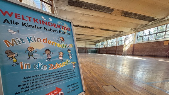 Ein Werbeschild mit der Aufschrift "mit Kinderrechten in die Zukunft" steht in einer Sporthalle.