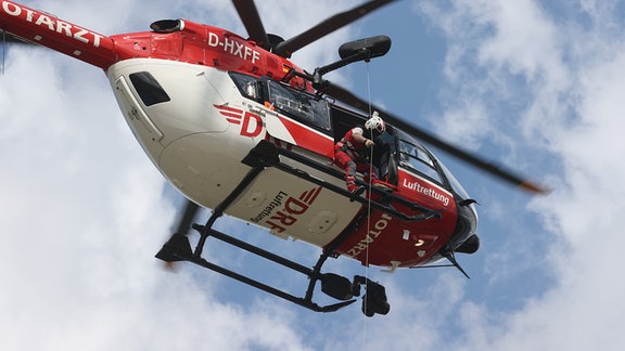 Ein Rettungshubschrauber der DRF Luftrettung in der Luft von unten gesehen