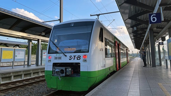 Eine Südthüringen-Bahn steht auf einem Gleis an einem Bahnsteig.