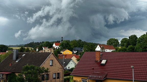 Eine Gewitterfront zieht sich über einem Dorf zusammen.