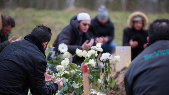 Gäste einer muslimischen Bestattung beten am geschlossenen Grab auf dem Landschaftsfriedhof Gatow in Berlin-Spandau.