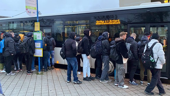 Menschen in der Dämmerung vor Bus