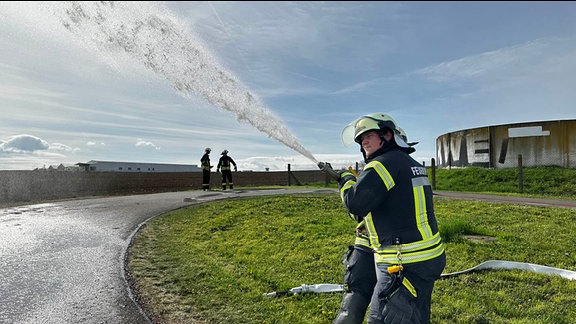 Ein Feuerwehrmann hält einen Löschschlauch.