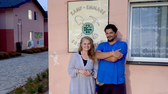 Frau und Mann stehen vor einer Hauswand