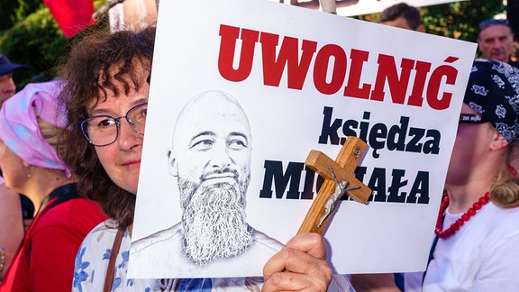 Ein von Recht und Gerechtigkeit organisierter Protest zur Verteidigung des angeblich gefolterten Priesters Olszewski. Frau mit Kreuz und Banner: Freier Pater Michal.