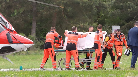 Rettungskräfte mit einem Patienten am Rettungshubschrauber