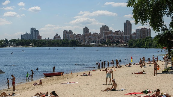 Menschen entspannen sich am 6. Juli 2024 am Strand am Ufer des Flusses Dnipro in Kiew