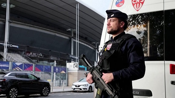 Ein bewaffneter  Polizist vor einem Stadion