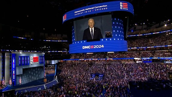 Der Parteitag der US-Demokraten: Präsident Joe Biden auf einer Videoleinwand, darunter zahlreiche Menschen