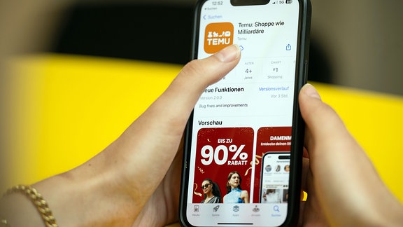 Eine Person hält ein Telefon mit der App Temu in den Händen.