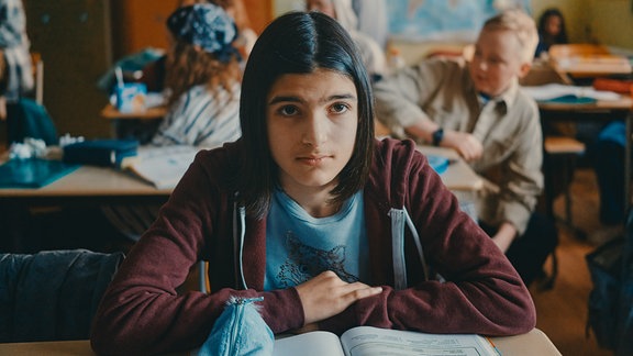 Dunkelhaariges Mädchen im Klassenzimmer.