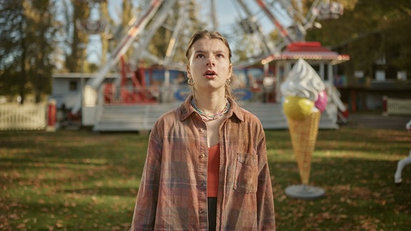 Szene aus der Neuverfilmung von "Spuk unterm Riesenrad": ein Mädchen steht staunend auf einem Jahrmarkt und blickt nach oben