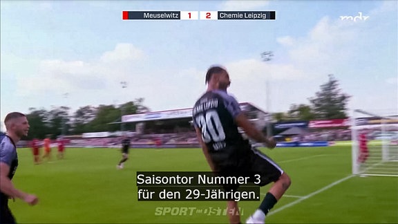 Fussballer mit schwarzem Trikot im Stadion beim Torschuss