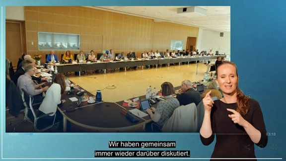 Eine Frau steht vor einem Bild auf dem ein Konferenzraum zu sehen ist.