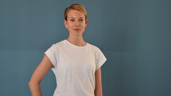 Eine blonde, junge Frau mit weißem T-Shirt.