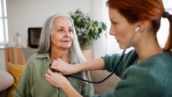 Eine Frau hört eine ältere Patientin ab.