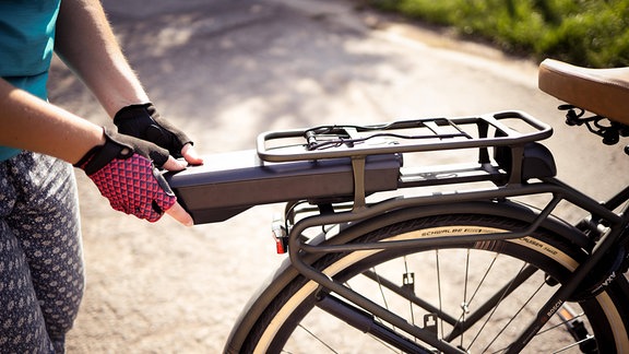 Radfahrerin beim Einsetzen der Batterie an einem Elektrofahrrad