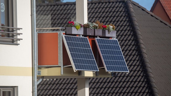 Solarmodule für ein sogenanntes Balkonkraftwerk hängen an einem Balkon. 